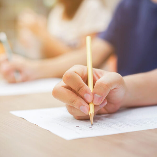 close up student hand using pencil for doing text exam after fin